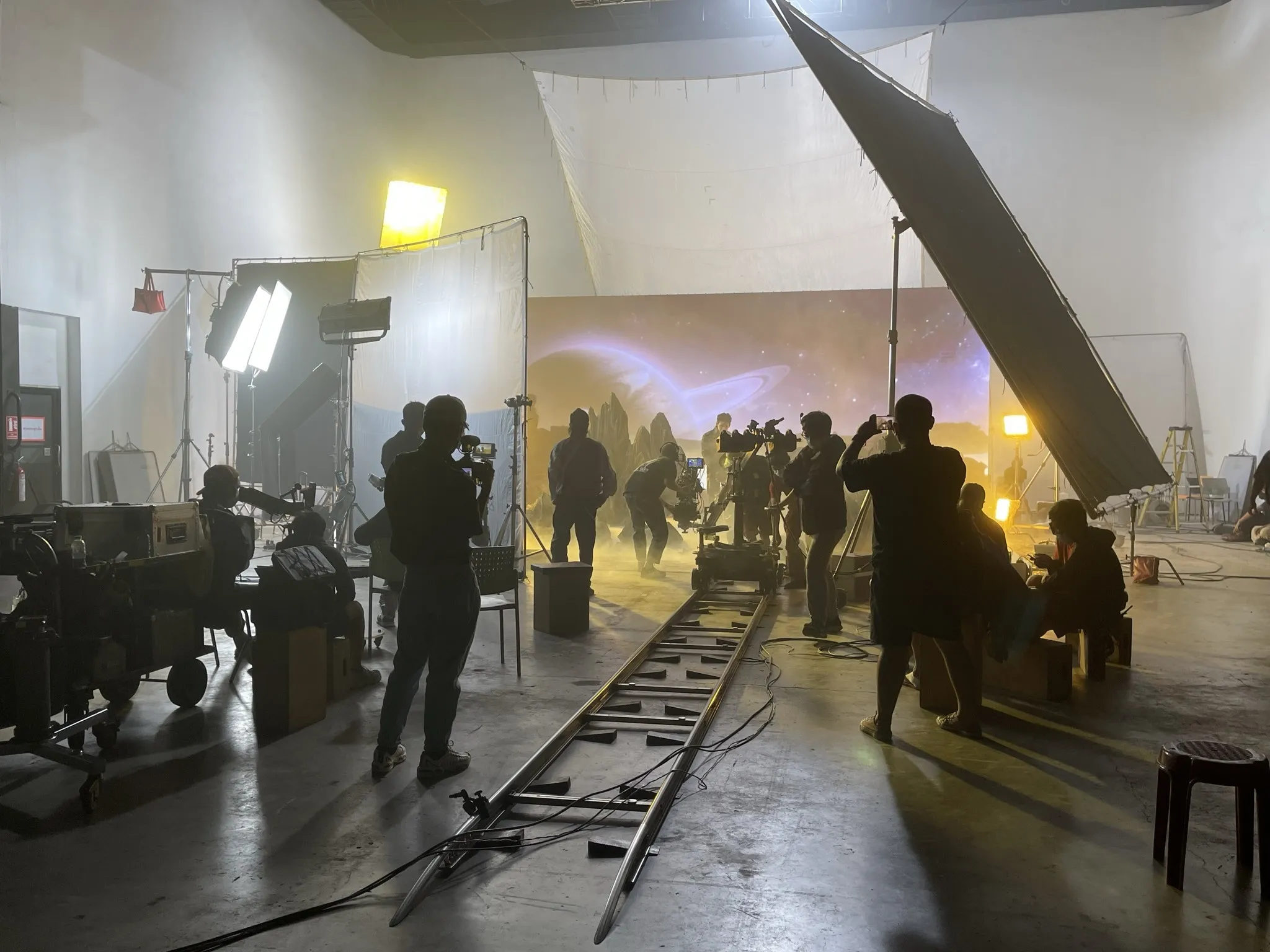 Camera crew and dolly track facing the gold planetary LED background on the ATLAS shoot