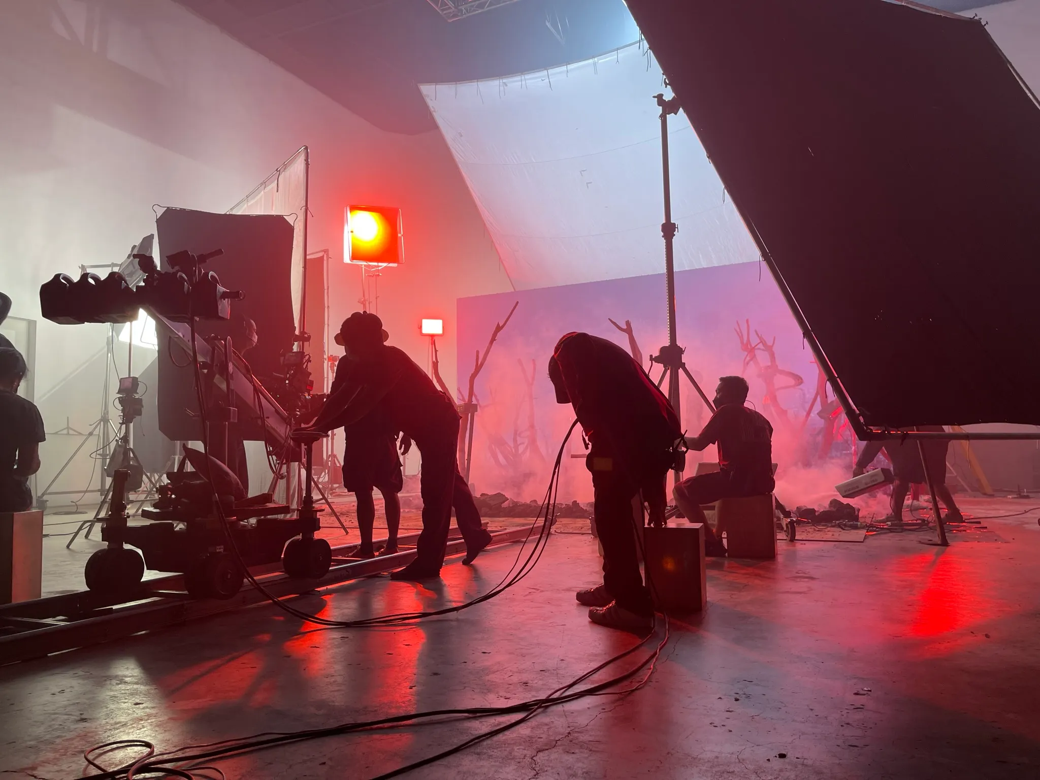 Crew with a camera crane on a red-lit set of bare branches during the ATLAS MAYDAY MAYDAY virtual production shoot