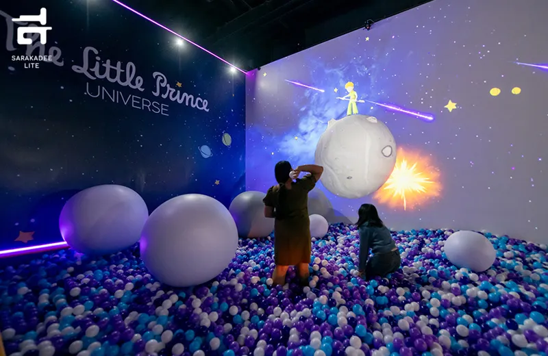 Visitors in a ball pit before a projected planet and the Little Prince at The Little Prince Universe
