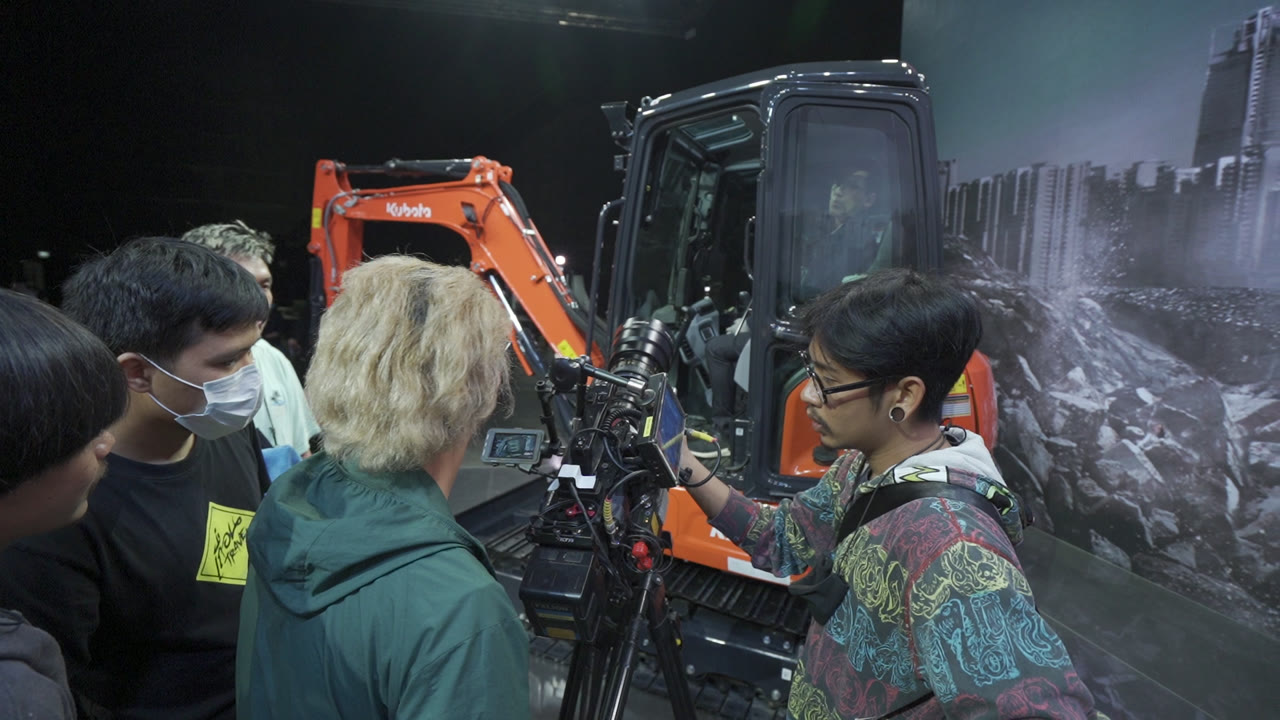 Camera crew working beside an orange Kubota excavator on the virtual-production stage.